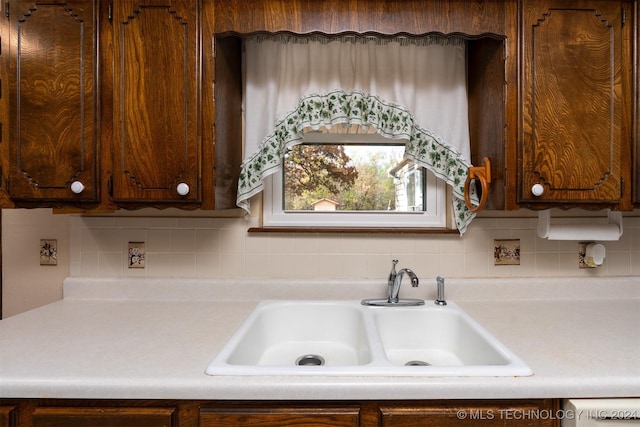 kitchen featuring decorative backsplash, dark brown cabinetry, and sink