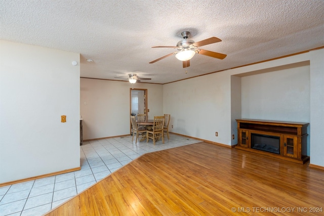 unfurnished living room featuring ceiling fan, light hardwood / wood-style floors, and a textured ceiling