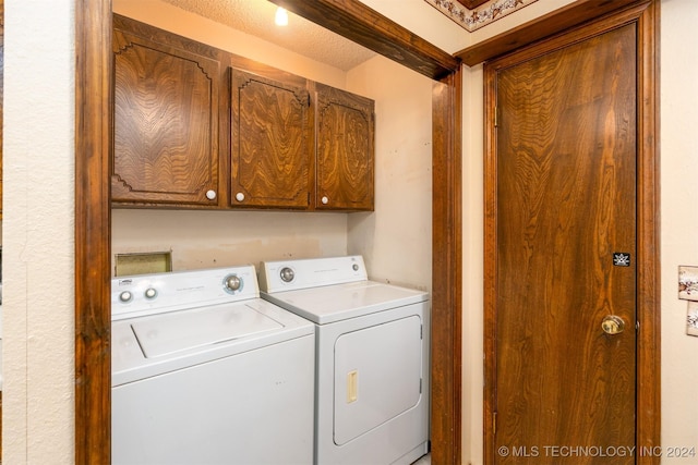 washroom featuring washer and dryer, cabinets, and a textured ceiling