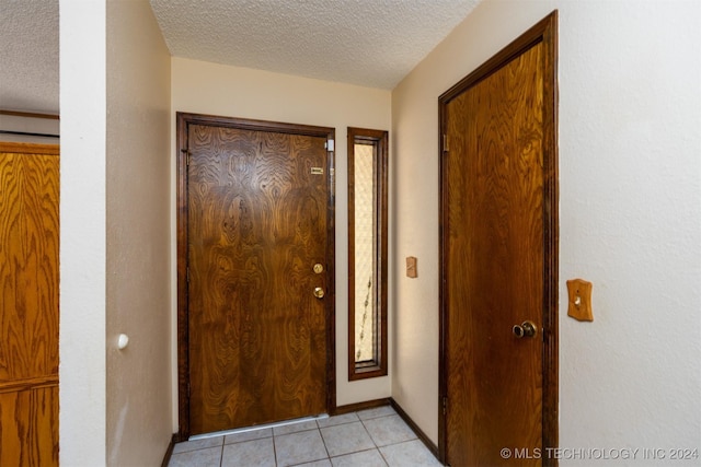 doorway to outside featuring light tile patterned floors and a textured ceiling