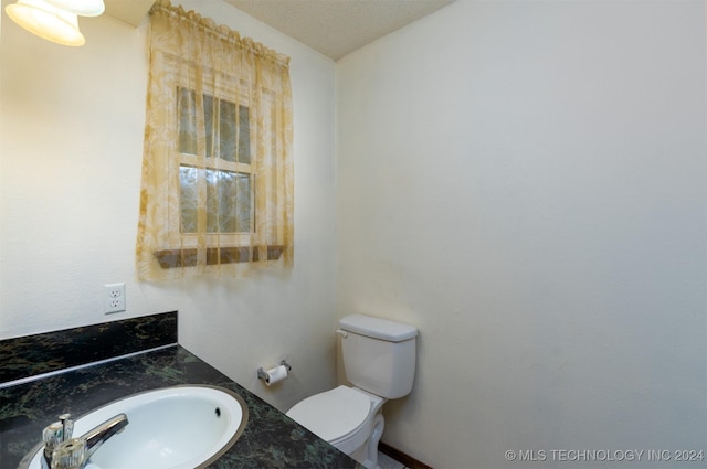 bathroom featuring a textured ceiling, vanity, and toilet