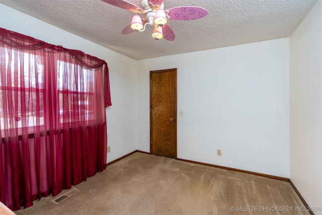 carpeted empty room featuring ceiling fan and a textured ceiling