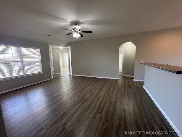 unfurnished living room featuring ceiling fan and dark wood-type flooring