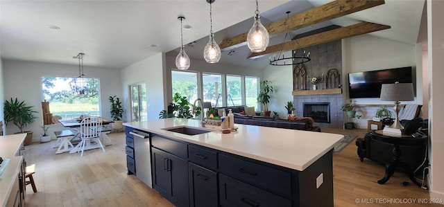 kitchen featuring vaulted ceiling with beams, sink, a kitchen island with sink, and decorative light fixtures