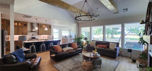 living room with vaulted ceiling with beams, light hardwood / wood-style floors, an inviting chandelier, and sink