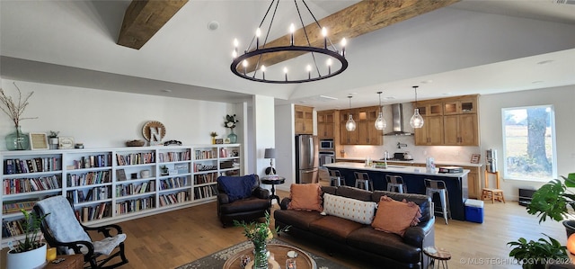 living room featuring vaulted ceiling with beams, an inviting chandelier, sink, and light hardwood / wood-style flooring