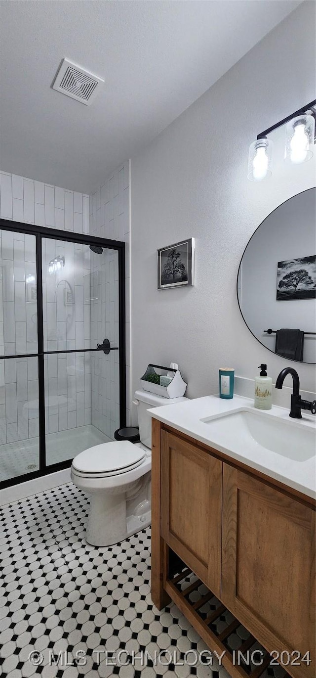 bathroom with an enclosed shower, vanity, toilet, and tile patterned flooring