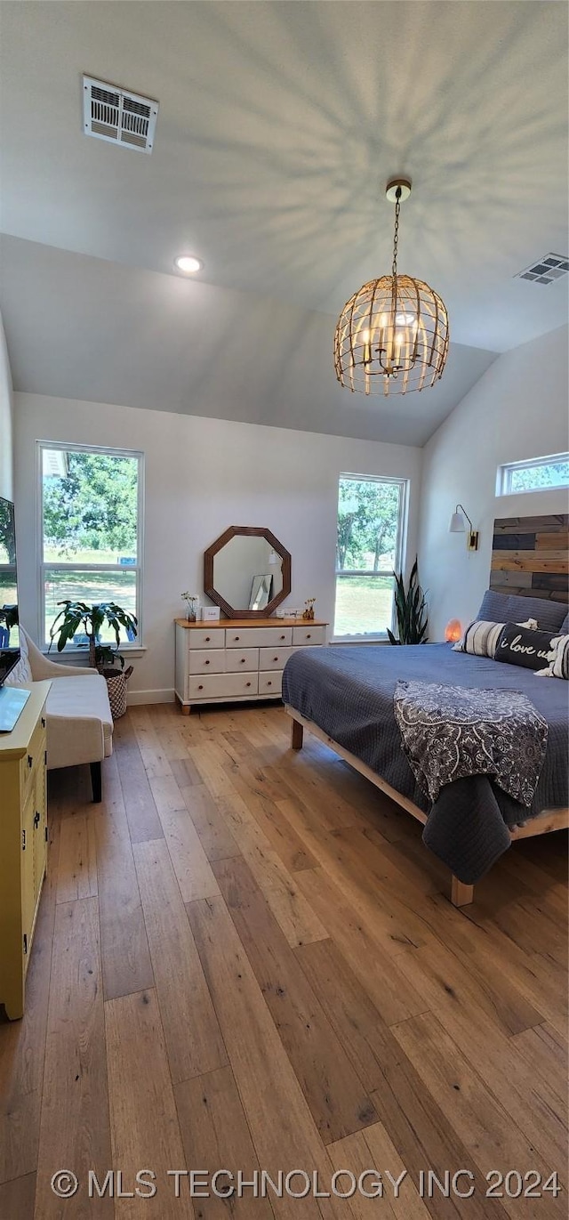 bedroom featuring multiple windows, wood-type flooring, lofted ceiling, and an inviting chandelier