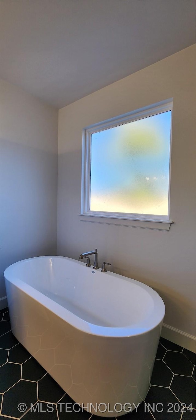 bathroom featuring tile patterned flooring, a healthy amount of sunlight, and a tub