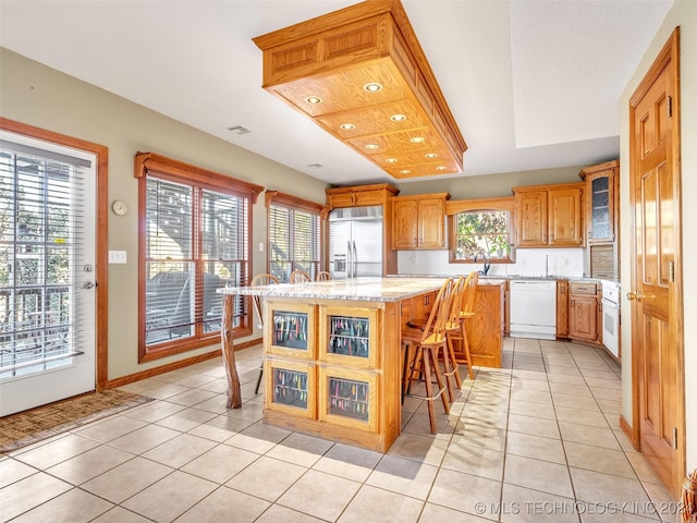 kitchen featuring dishwasher, a center island, stainless steel built in refrigerator, a breakfast bar area, and light tile patterned floors