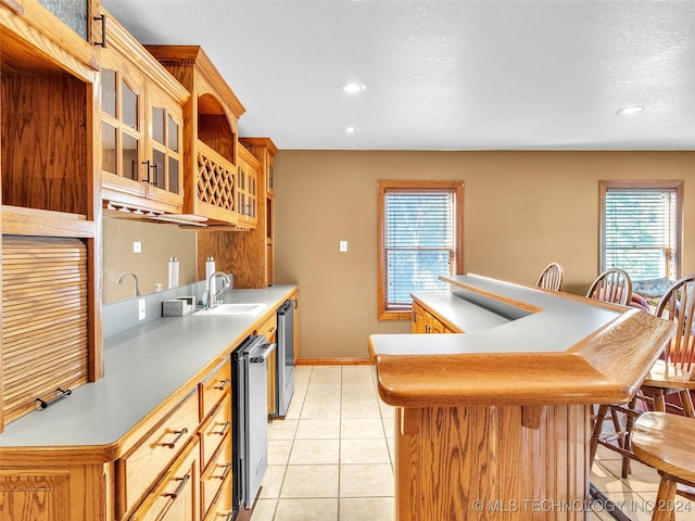 kitchen with a textured ceiling, sink, light tile patterned floors, wine cooler, and a breakfast bar area