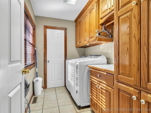 washroom with cabinets, washing machine and clothes dryer, and light tile patterned flooring