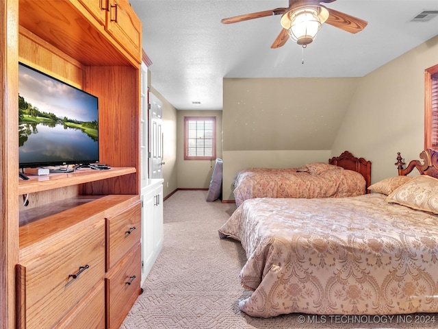 bedroom with a textured ceiling, light colored carpet, vaulted ceiling, and ceiling fan