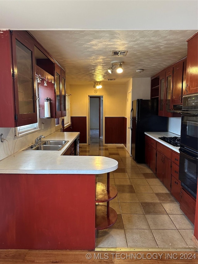 kitchen featuring black appliances, sink, kitchen peninsula, a breakfast bar area, and light tile patterned flooring