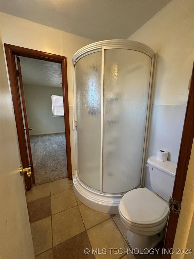 bathroom with an enclosed shower and tile patterned flooring