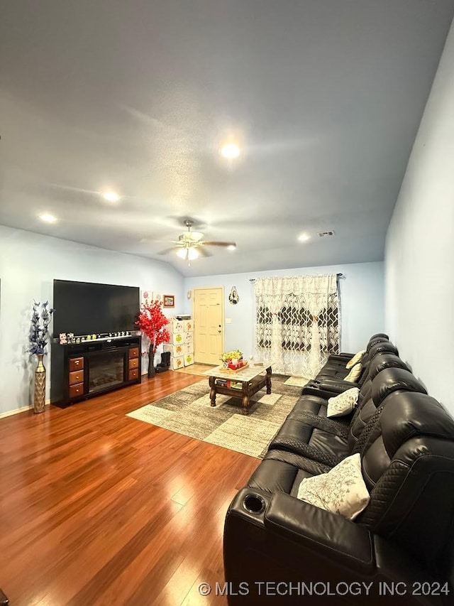 living room featuring wood-type flooring, ceiling fan, and a fireplace