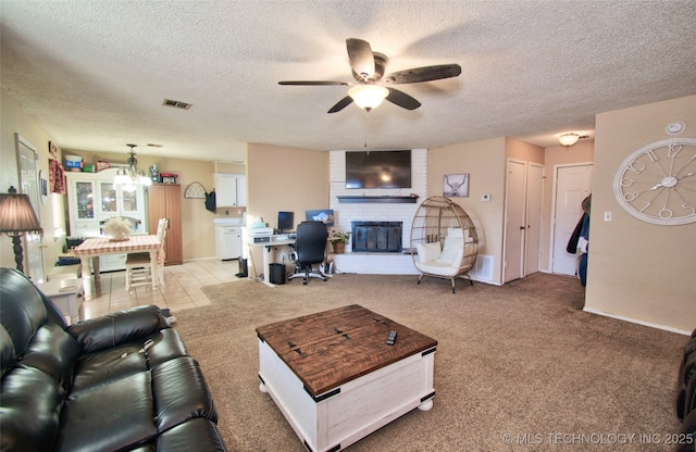 living room featuring a fireplace, a textured ceiling, ceiling fan, and light carpet