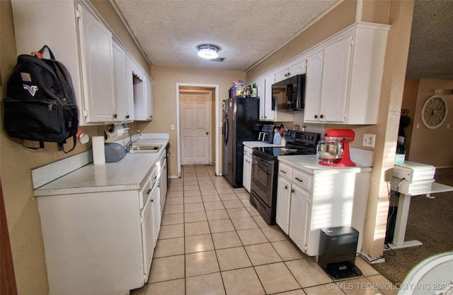 kitchen with sink, white cabinets, a textured ceiling, light tile patterned floors, and black appliances