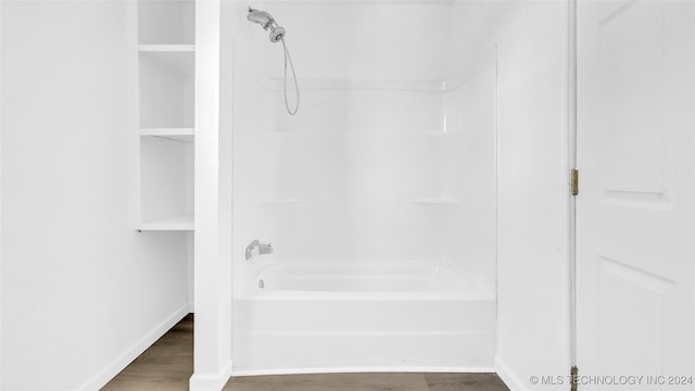 bathroom with hardwood / wood-style floors and bathing tub / shower combination