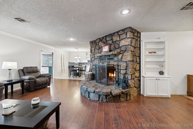 living room featuring a fireplace, a textured ceiling, hardwood / wood-style flooring, and crown molding