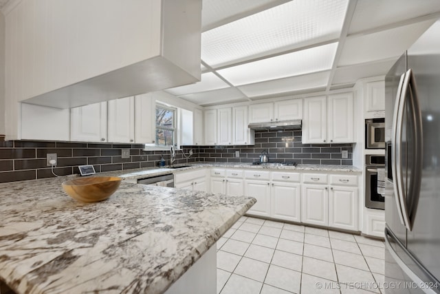 kitchen featuring light stone countertops, backsplash, white cabinetry, and stainless steel appliances