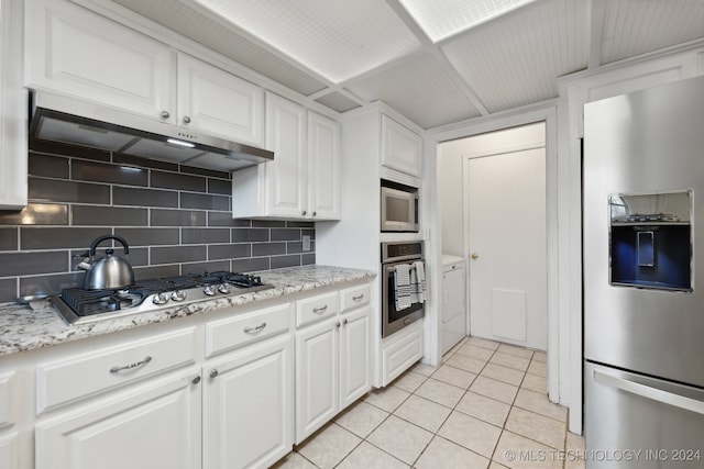 kitchen featuring decorative backsplash, light stone countertops, stainless steel appliances, light tile patterned floors, and white cabinetry