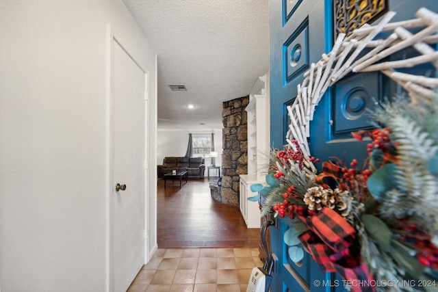 hallway featuring ornate columns, light hardwood / wood-style floors, and a textured ceiling