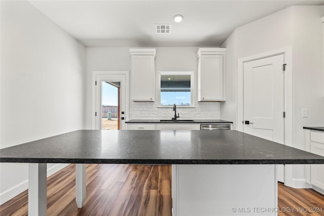 kitchen with white cabinets, hardwood / wood-style flooring, a kitchen island, and sink