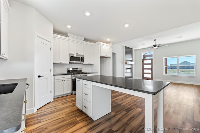 kitchen featuring dark wood-type flooring, ceiling fan, a kitchen bar, white cabinetry, and stainless steel appliances