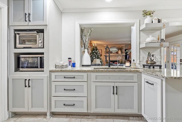 kitchen with kitchen peninsula, crown molding, sink, and light stone counters