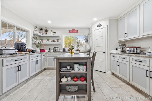 kitchen featuring light stone countertops, white cabinetry, crown molding, and light tile patterned flooring