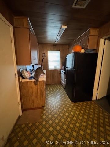 kitchen featuring wood walls, black refrigerator, and wood ceiling