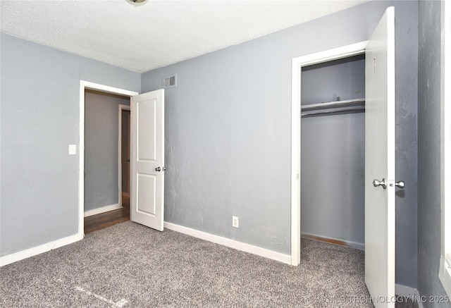 unfurnished bedroom featuring a closet, dark carpet, and a textured ceiling