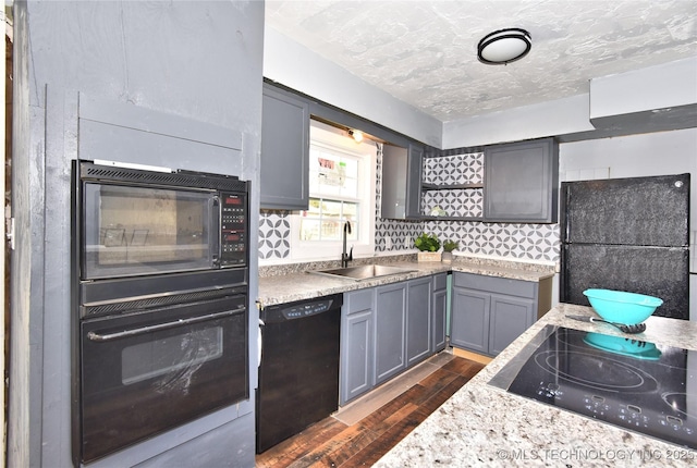 kitchen featuring sink, dark wood-type flooring, tasteful backsplash, a textured ceiling, and black appliances