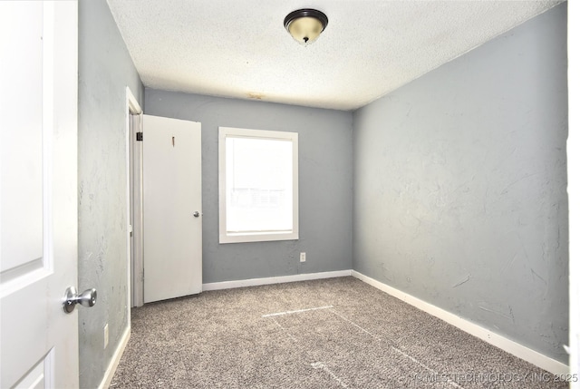 spare room with a textured ceiling and dark carpet