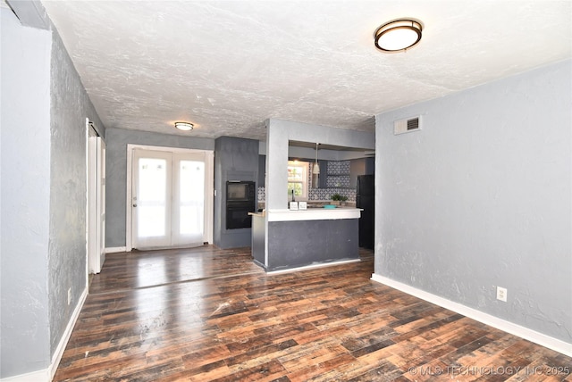 unfurnished living room with dark wood-type flooring and a textured ceiling