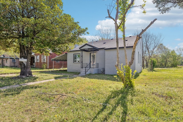 1006 N K St, Muskogee, OK 74403 - back of property featuring brick siding, a yard, and an attached carport
