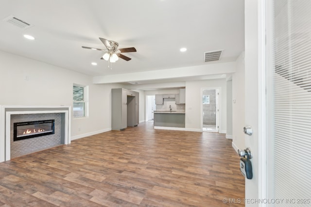 1006 N K St, Muskogee, OK 74403 - unfurnished living room featuring a ceiling fan, dark wood-style flooring, recessed lighting, a glass covered fireplace, and plenty of natural light