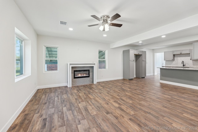 1006 N K St, Muskogee, OK 74403 - unfurnished living room featuring dark wood finished floors, a glass covered fireplace, a ceiling fan, and recessed lighting
