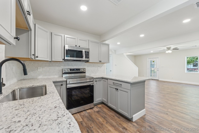 1006 N K St, Muskogee, OK 74403 - kitchen featuring appliances with stainless steel finishes, a peninsula, recessed lighting, dark wood-style floors, and decorative backsplash