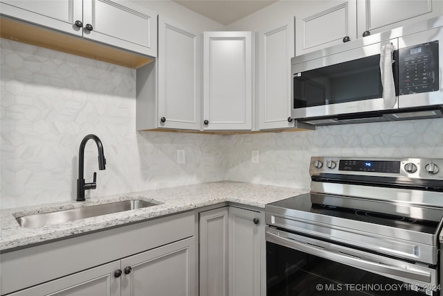 kitchen with white cabinetry, sink, light stone counters, and appliances with stainless steel finishes