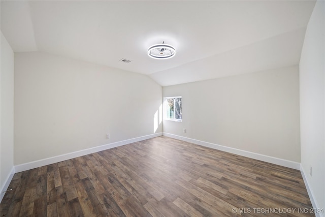 unfurnished room featuring dark hardwood / wood-style floors and vaulted ceiling