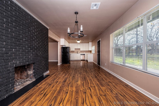 unfurnished living room with a fireplace, dark hardwood / wood-style flooring, and a notable chandelier