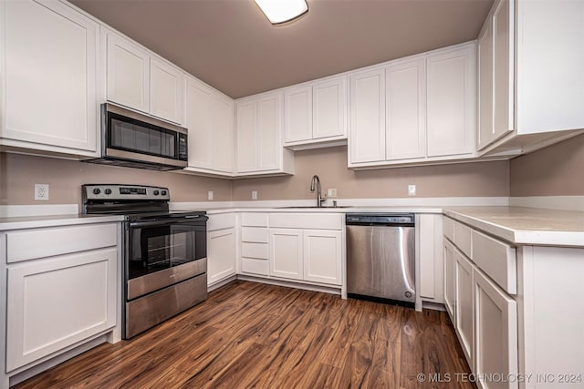 kitchen featuring appliances with stainless steel finishes, dark hardwood / wood-style flooring, white cabinetry, and sink