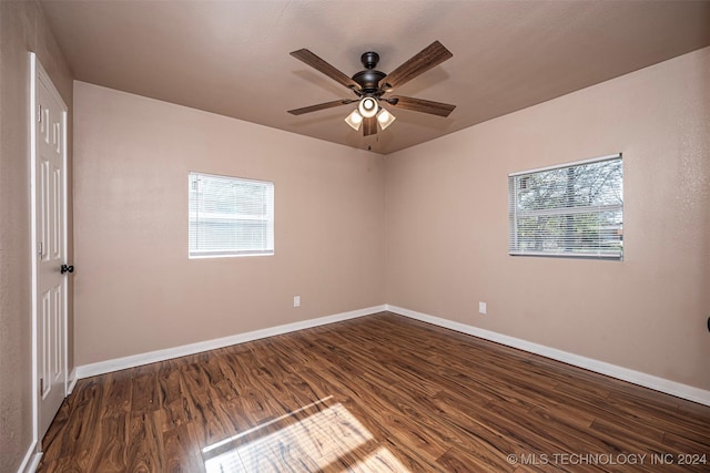 empty room with ceiling fan, plenty of natural light, and dark wood-type flooring