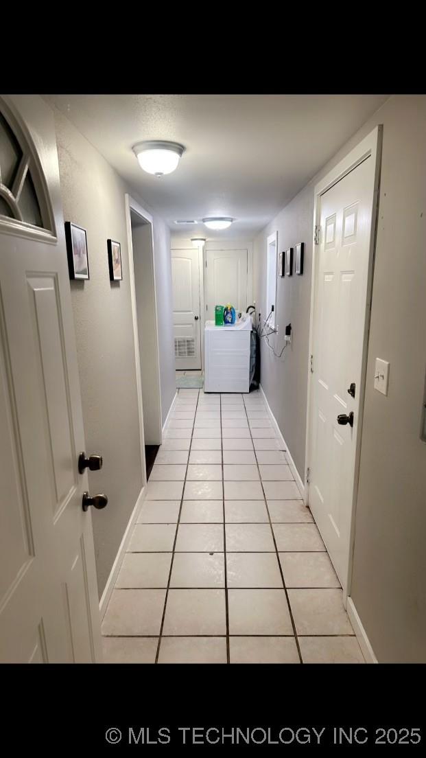 corridor with light tile patterned flooring and washer / dryer