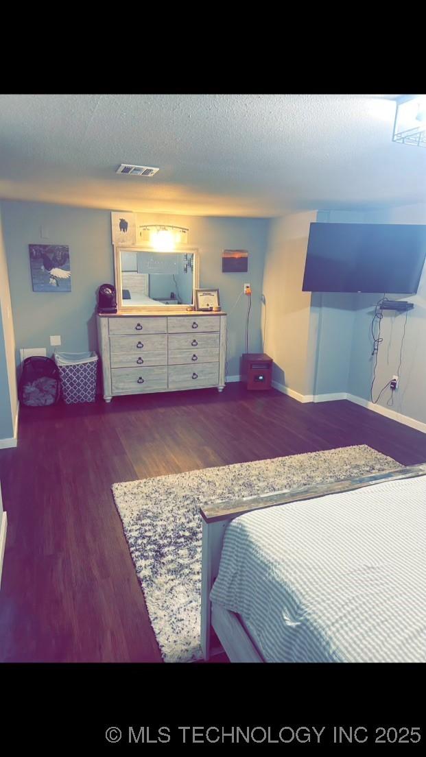 bedroom with dark hardwood / wood-style floors and a textured ceiling