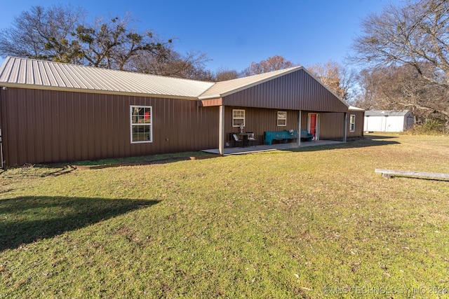 back of house featuring a lawn, a storage unit, and a patio