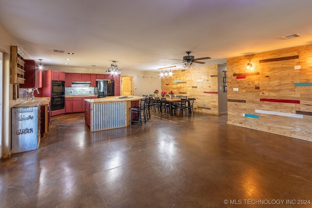 kitchen with sink, a breakfast bar area, backsplash, a center island, and black appliances