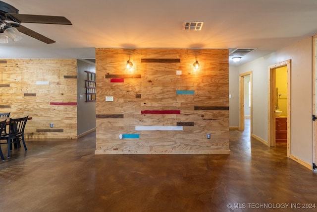 interior space with ceiling fan and wooden walls